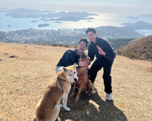 Two of the alumni in a photo with two pet dogs.